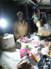 A vendor in her stand, illuminated by a LED lamp, in a Karagita market.